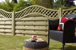 a low wooden hit and miss fence with a curved trellis top behind a garden chair and stool
