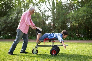 a grandad pushing a boy on a trolley in the garden
