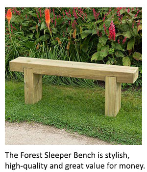 The Forest Sleeper Bench positioned between a path and a flowerbed.