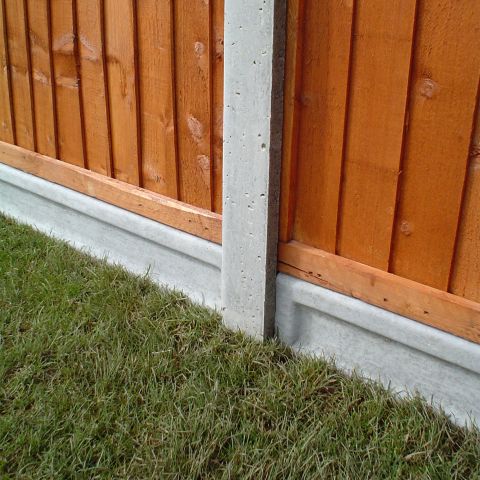concrete gravel boards and post supporting fence panels atop some grass
