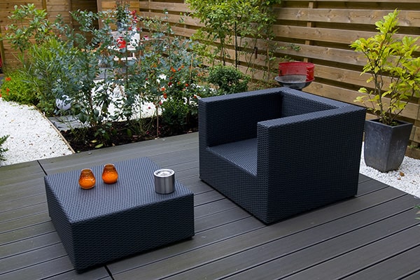 a black, modern garden seat and coffee table on a decked area