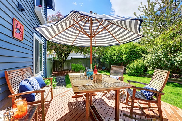 a garden table, chairs and parasol on a wooden deck