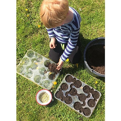 a boy planting seeds in a seed tray