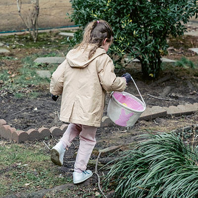 a girl holding a bucket, running in the garden