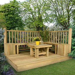 A wooden garden decking kit, including railings positioned at a right angle and a wooden garden table positioned on the decking boards.