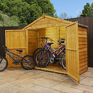The 6'7x2'8 Windsor Overlap Bike Store, situated on a patio and with its doors open to reveal 3 bikes.