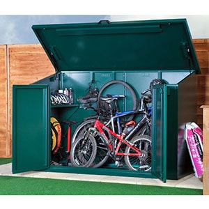 The 7x3 Asgard Access Metal Bike Storage Shed, situated on paving slabs, next to a fence, and with its lid up and doors open to reveal 3 bikes and cycling accessories.