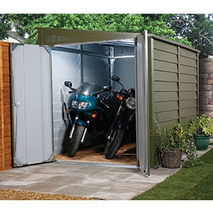 The 9x5 Trimetals Protect-a-Bike Secure Garden Storage, located in the corner of a garden, with its doors open to reveal 2 motorbikes.