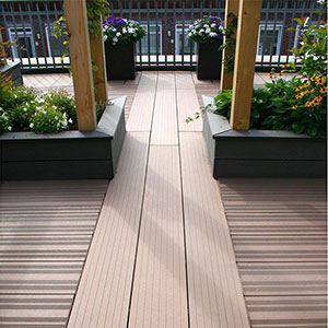 Brown composite deck boards leading out to a roof terrace, which is decorated with planters.