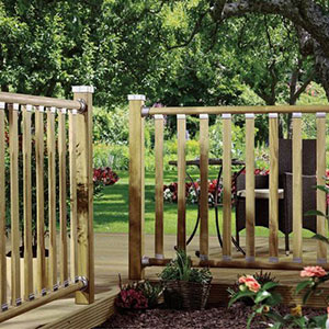 Wooden railings with chamfered deck spindles, at the edge of a wood deck, which leads to a lawn.